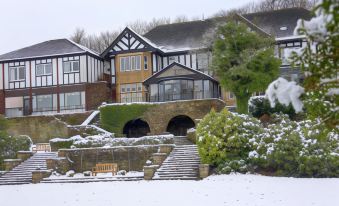 a large house with a stone staircase leading to it is surrounded by snow - covered trees and bushes at Burnley West Higher Trapp Hotel