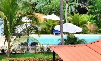 a resort with a pool surrounded by palm trees , umbrellas , and lounge chairs , as well as a red roof at Hostal la Casona