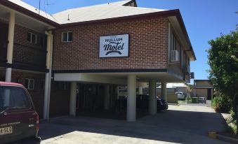 "a brick building with a sign that reads "" napoleon motel "" prominently displayed on the side of the building" at The Mullum Motel