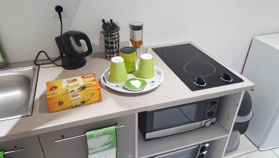 a kitchen counter with a microwave , a coffee maker , and two cups of coffee on a tray at Vichy