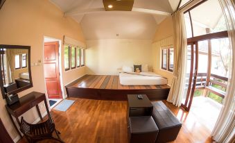 a large , open room with wooden floors and walls has a bed on the left side and a chair on the right at Baan Suan Nuanta