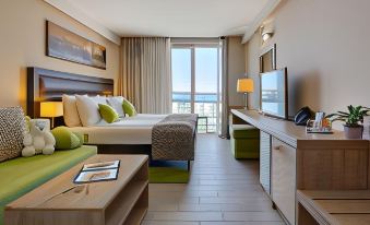 a modern hotel room with a bed , desk , and tv , as well as a balcony offering views of the city at Hotel Pinija