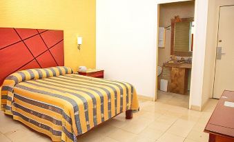 a hotel room with a bed , nightstand , and doorway leading to a bathroom with a sink at Hotel Paradise Inn