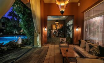 a modern living room with wooden flooring , white furniture , and oriental lanterns hanging from the ceiling at Tikida Golf Palace