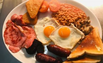 a white plate filled with a variety of breakfast foods , including eggs , bacon , sausage , and toast at The Queen Victoria