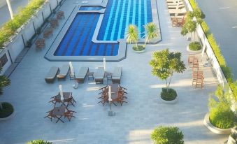 an aerial view of a swimming pool area with lounge chairs , umbrellas , and trees , surrounded by buildings at The Mangrove Hotel