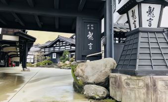 a traditional japanese house with a stone gate and a large rock in front of it at Ryugon