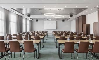 a large conference room with multiple rows of chairs arranged in a semicircle around a table at Courtyard Basel