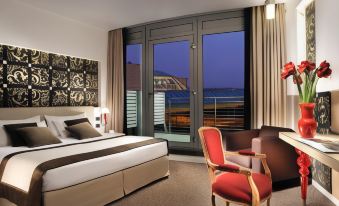 a modern bedroom with a large bed , red chairs , and a view of the city through a large window at Antony Palace Hotel - Venice Airport