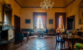 a living room with a wooden floor , a large window , and two people sitting at a table at Castello di Semivicoli