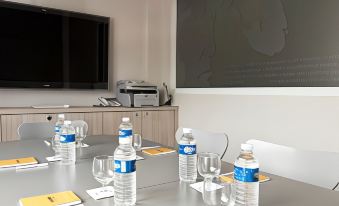 a conference room with a projector screen , water bottles , and empty glass bottles on the table at Hotel Victoria