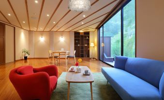 a modern living room with a blue couch , red and blue chairs , wooden floors , and large windows at Moritaya