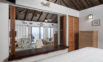 a room with a wooden table and chairs , a hanging lamp , and a view of the ocean at Point Pleasant Resort