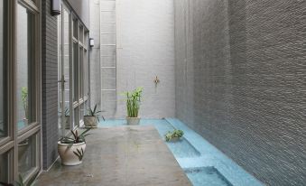 a modern , minimalist interior with white walls and grey concrete flooring , featuring a blue tiled floor and potted plants at Micasa Hotel