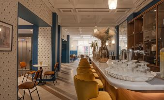 a restaurant with blue walls , wooden floors , and white tables and chairs , as well as a bar area with multiple stools at Hôtel le Bristol