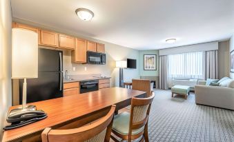 a kitchen and dining area with a wooden table , chairs , and a refrigerator are shown at Comfort Inn & Suites