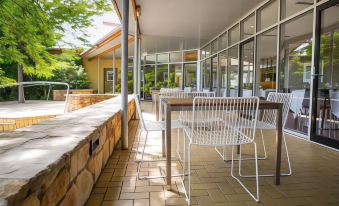 a patio with several white chairs and a dining table set up for outdoor dining at Royal Mail Hotel