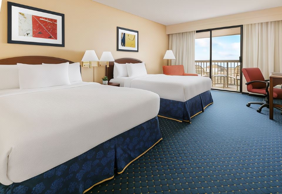 a hotel room with two beds , a large window , and a balcony view , all decorated in blue and white colors at Courtyard Flint Grand Blanc