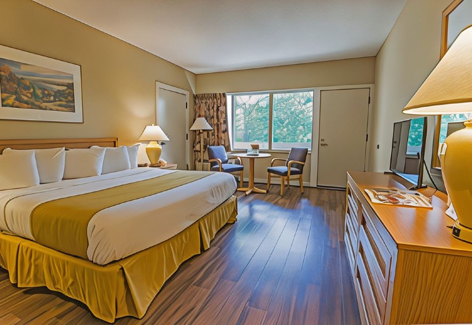 a hotel room with a king - sized bed , hardwood floors , and a flat - screen tv . also a dining table and chairs in the at General Butler State Resort Park