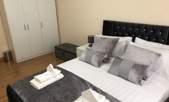 a bed with a white headboard and gray linens is shown in a bedroom next to a dresser at Green Apartments