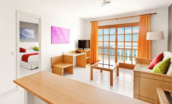 a living room with a wooden table , chairs , and a television is shown next to a bedroom at Elba Castillo San Jorge & Antigua Suite Hotel