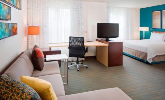 a modern hotel room with a couch , chair , desk , bed , and tv , along with curtains and a window at Residence Inn Saddle River