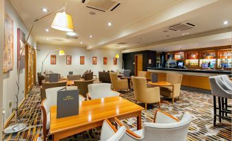 a modern lounge area with wooden tables , chairs , and a bar in the background at The Park Royal Hotel & Spa