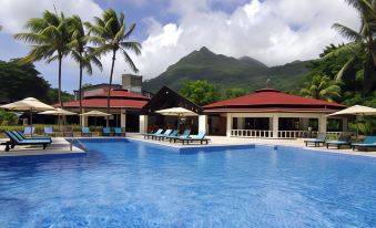 a large outdoor pool surrounded by multiple buildings , with palm trees in the background at Berjaya Beau Vallon Bay Resort & Casino