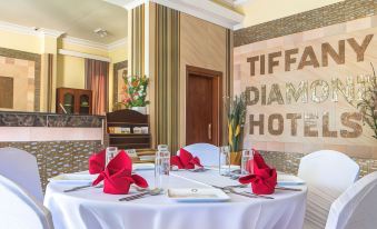 a dining room with a table set for a formal dinner , complete with white tablecloths and red napkins at Tiffany Diamond Hotels - Mtwara