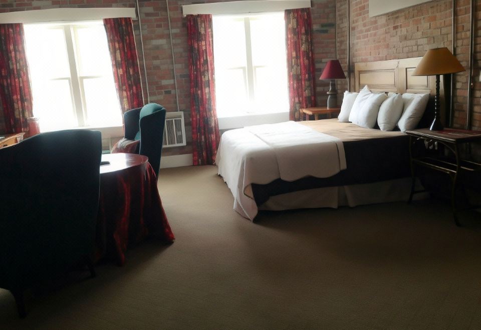 a large bed with white linens is situated in a room with brick walls and windows at William Watson Hotel