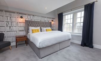 a modern bedroom with a large bed , gray headboard , and white linens , along with two lamps on either side of the bed at The Lawrence
