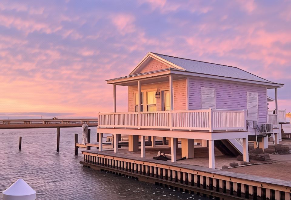 a wooden house with a balcony and pink and purple colors is situated on a pier at Key West Cottages