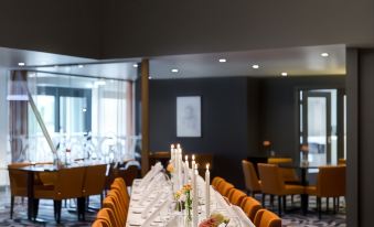 a long dining table is set with wine glasses , candles , and flowers in a room with a chandelier at Quality Hotel Entry