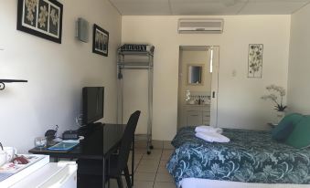 a modern hotel room with white walls , black furniture , and a bed , as well as a desk and window at Black Marlin Motel