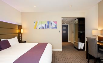 a hotel room with a large bed , a door , and a painting on the wall at Premier Inn Oban