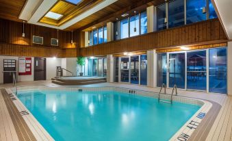 a large indoor swimming pool with a wooden ceiling and walls , surrounded by windows and stairs at Ramada by Wyndham Jacksons Point