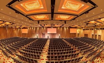 a large , well - lit auditorium with rows of black chairs and wooden paneling on the walls at Pullman Melbourne Albert Park