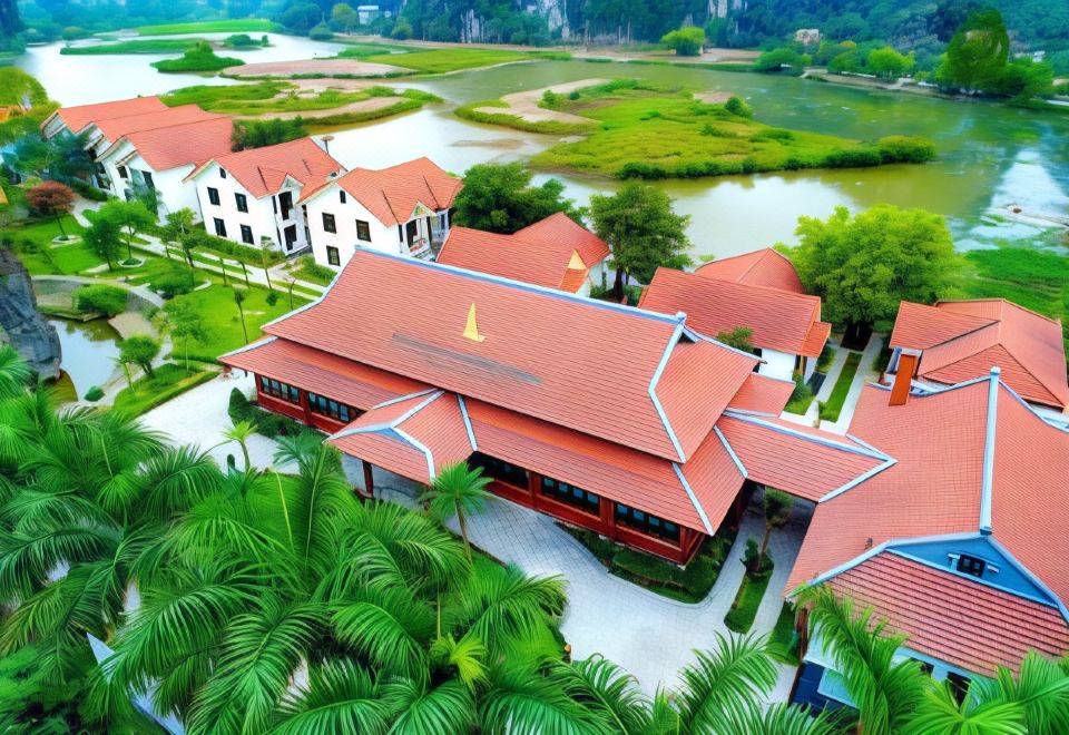 a bird 's eye view of a building with red roofs and palm trees surrounding it at Tam Coc La Montagne Resort & Spa