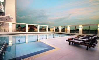 a rooftop pool with several lounge chairs and a view of the city skyline in the background at Kantary Hotel Kabinburi