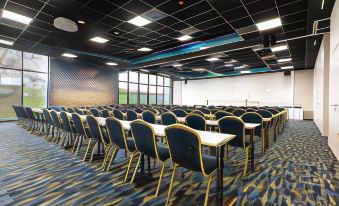 a large conference room with rows of chairs and tables , a projector screen , and a window at Hotel Atlantis