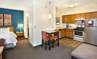 a kitchen and dining area with a table , chairs , cabinets , stove , microwave , refrigerator , and lamps at Residence Inn Saddle River
