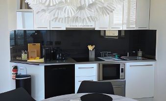 a black and white kitchen with a dining table set for four people , surrounded by white cabinets and a bar counter at Saltwater - Absolute Oceanfront, Hot Tubs, Sauna, Fire Pits