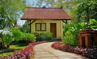 a small house with a red tile roof is surrounded by greenery and has a path leading to it at Tlogo Resort & Goa Rong View Ungaran