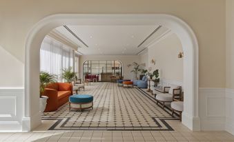 a large , open living room with a black and white tiled floor , orange couches , and several chairs at Resort Hadera by Jacob Hotels