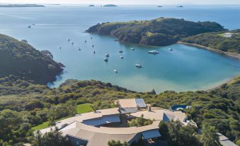 a beautiful aerial view of a house nestled on the edge of a body of water , surrounded by lush greenery at Delamore Lodge