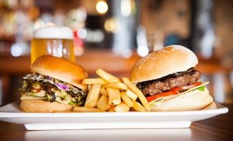 a plate of food , including two burgers and french fries , placed on a dining table at Nightcap at Westside Hotel