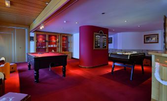 a room with a red carpeted floor and two pool tables , one on the left and the other on the right at Hotel l'Eden des Cimes - Vacances Bleues - Belle Plagne 2100