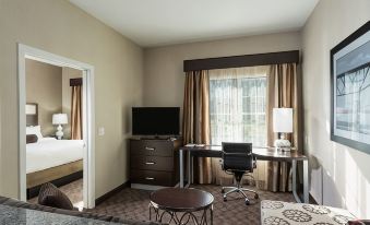 a modern hotel room with a desk , chair , and tv , along with a couch and other furniture at Residence Inn Boston Needham