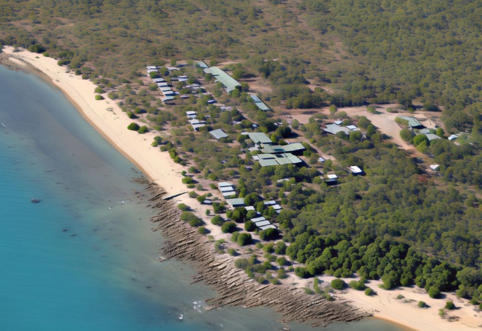 aerial view of a beach with houses and trees , surrounded by the water on a sunny day at Groote Eylandt Lodge