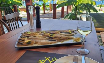 a wooden dining table with a plate of food , wine glasses , and a bottle of wine at Royal Hotel and Suites